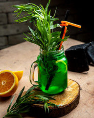 a mason jar with tarragon drink garnished with tarragon and lemon slice