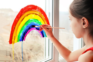 Schoolgirl draws rainbow sign of hope on window