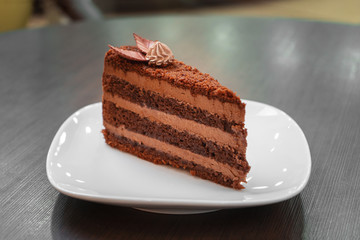 Chocolate cake on a white plate on a wooden table.