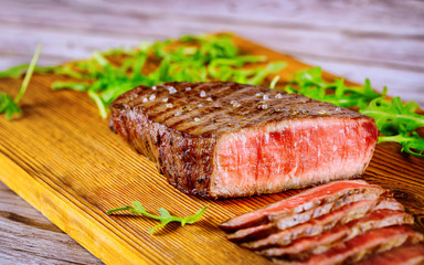 Grilled rare angus beef steak on wooden board.