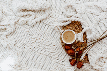 Fototapeta na wymiar Flat lay cup of coffee and roses over plaid blanket on rattan straw. Morning breakfast. Minimal modern interior design concept. Still Life concept