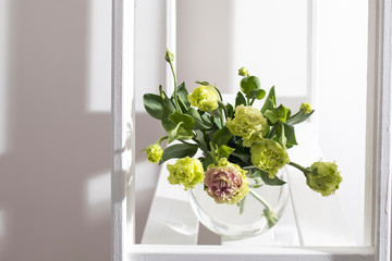 Bouquet of green and pink terry lisianthus and eucalyptus branches in a transparent round vase on white background. Bride bouquet