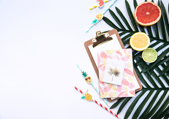 Creative flat lay with Exotic tropical monstera palm leaf and home office stationery on minimal background with summer fruits.