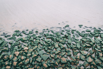 green moss rocks on side of lake river