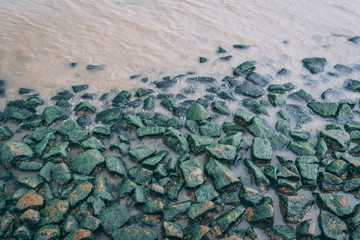 green moss rocks on side of lake river