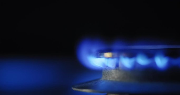 Close-up view of kitchen stove with blue gas flame burning. Concept of environment and energy