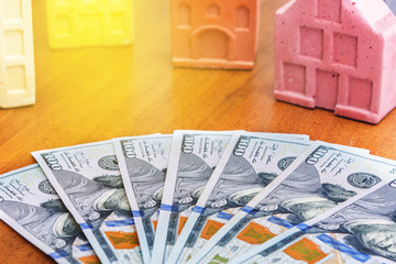 Dollars on a table with small houses and sunshine