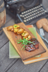 steak with potatoes and herbs on a wooden board