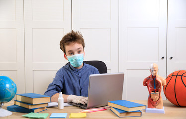 schoolboy in medical mask studying at home. Distance learning online education, coronavirus quarantine