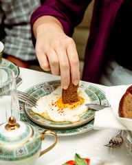 man dipping a bread into sunny side up egg served for breakfast