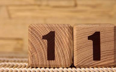 The number eleven on a wooden cube on a beige background. Cube on a bamboo Mat.