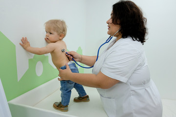 a medical worker with a stethoscope examines a small child. one year old baby at a pediatrician's appointment