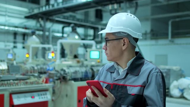 Asian chinese Korean professional male engineer business man in hard hat working on engineering industrial manufacturing facility using mobile phone smartphone. worker architect inspection slow-mo 4 K