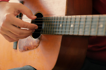 Close-up of mans hands playing an acoustic guitar. Playing the guitar, musical background.