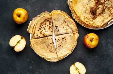 Thin homemade pancakes with apples on a stone background