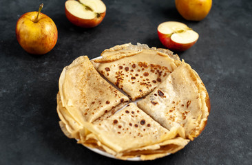 Thin homemade pancakes with apples on a stone background