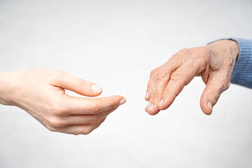 Helping hand for the elderly concept with young hand and old hand.