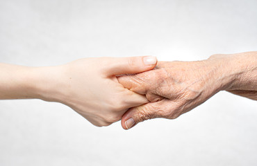 Helping hand for the elderly concept with young hand holding old hand.