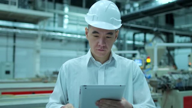 Asian, chinese Korean professional male engineer man business people in hard hat working on engineering industrial manufacturing facility using tablet indoors, worker architect inspection, slow-mo 4 K