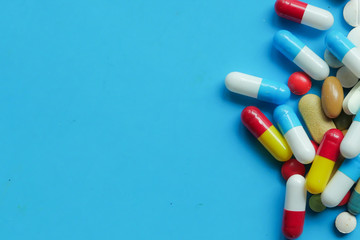 colorful pills and capsule on blue with copy space 