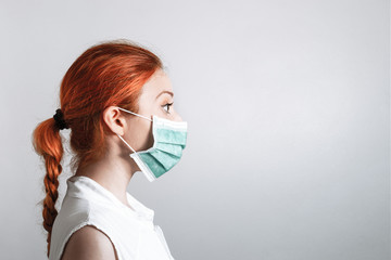 GINGER HAIR GIRL WITH BRAID AND BLUE SURGICAL MASK. WHITE BACKGROUND. COVID 19
