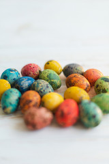 Fototapeta na wymiar Multi-colored quail Easter eggs on a white wooden background