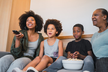 Grandmother, mother and children watching a movie at home.
