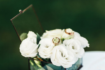 wedding rings lie on white eustomas in a glass casket. wedding ceremony concept