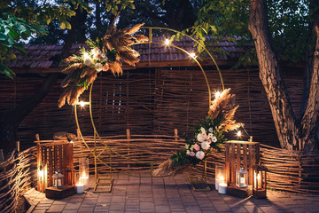Rustic style wedding ceremony arch, decorated with flowers, reeds, candles