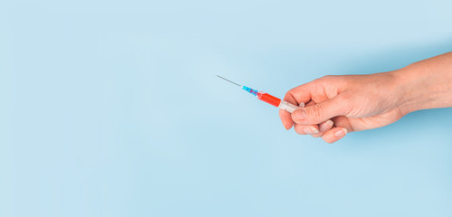 banner hand stretches out a syringe with medicine