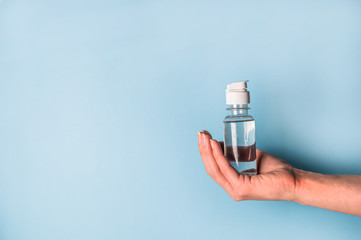 hand holds antiseptic on a blue background