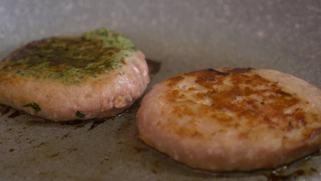 turning two hamburgers in a non stik pan with a skimmer - close up