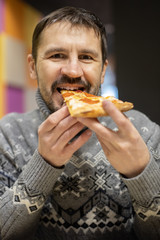 .Bearded man eating pizza in a cafe