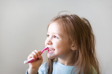 child brush their teeth. dental hygiene. happy little girl looks to the left