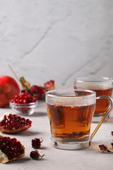 Pomegranate tea in two transparent cups on a gray concrete background, vertical format, Space for text