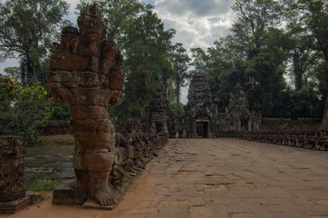 Entrance gate to Preah Khan temple and bridge over canal decorated statues of ancient khmer warrior heads carry giant snake .Angkor Wat Temple Complex, Siem Reap, Cambodia.