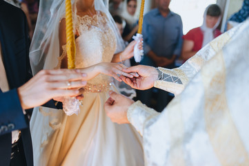 The priest holds a wedding ceremony in the church, rites and puts gold rings on the fingers of the...