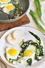 fried eggs with wild garlic as a shakshuka. fried eggs in a frying pan under gray marble on a table. Keto diet dish