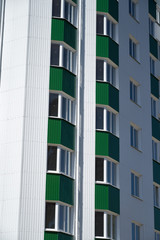 facade of a new multistory building with white and green metal siding, many Windows