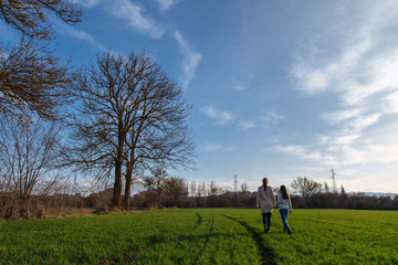 Two sisters walk on the field on a sunny day