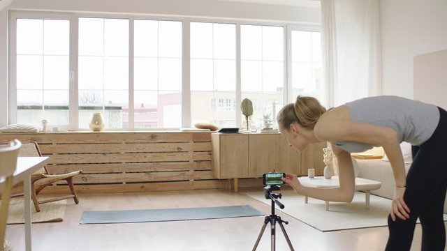 Attractive Caucasian female starting live stream or vlog about doing yoga at home. Stay home, quarantine workout. Shot on ARRI Alexa Mini with Cooke S4 lenses