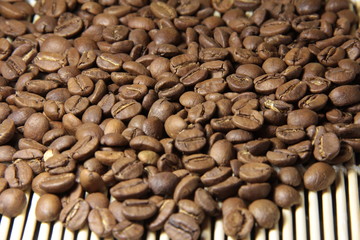 Coffee beans are scattered on a bamboo Mat