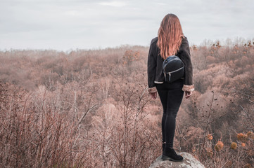 A white girl stands on a rock and looks into the distance