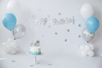 Festive background decoration for birthday celebration with gourmet cake and blue balloons in studio, cake smash first year concept - 337803777