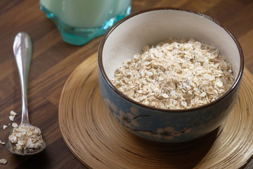 Rolled oats or oat flakes in wooden bowl on table