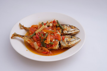 fried fish with chili sauce and tomatoes on top isolated white background