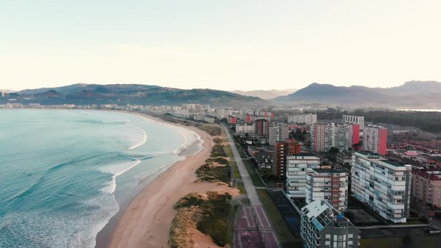 Aerial drone view of a coast skyline village next to the sea. Beach bay sunset with dunes in Laredo. Ideal for surfing.
