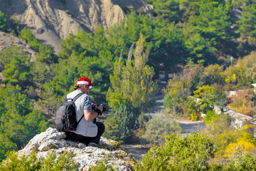 male tourist photographer sits on a mountain and takes pictures of beautiful mountain landscapes