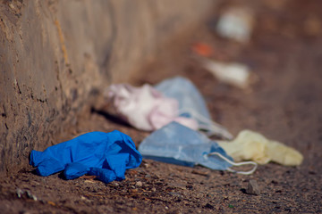 Used medical face masks and gloves on the ground outdoor. Environmental pollution concept