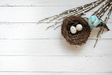 Easter background. Nest with easter eggs and decorative blue bird on wooden background.